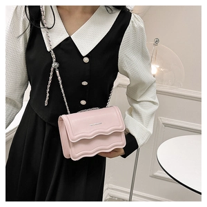 Vue détaillée d'un petit sac rose à rabat ondulé avec bandoulière chaîne sur un modèle