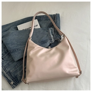 Détail du sac hobo en cuir rose poudré avec bandoulière réglable sur du denim