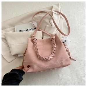 Dettaglio borsa tote rosa con trama marmorizzata, manico intrecciato e ciondolo di peluche