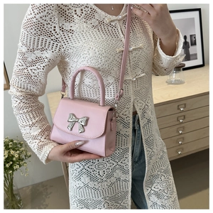 Dettaglio di una mini borsa rosa a tracolla con fiocco in metallo e manico superiore