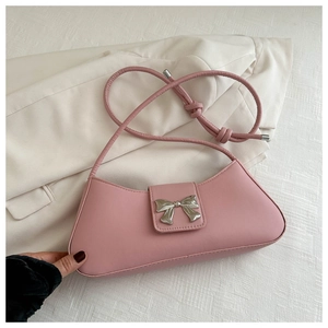 Close-up of pink faux leather shoulder bag with a silver bow clasp and knot strap detail