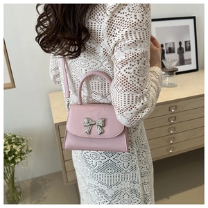 Detailed view of pink leather handbag featuring a stylish silver metallic bow ornament