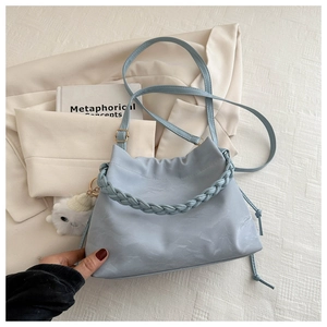 Dettaglio borsa tote blu in pelle PU con manico intrecciato e ciondolo peluche