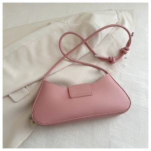 Detail view of pink minimalist baguette bag with knot shoulder strap on a beige blazer