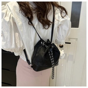 Detail of black drawstring bucket bag with silver chain and white fur ball charm accessory