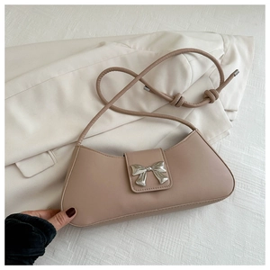 Detail of elegant beige leather handbag featuring a silver butterfly metallic buckle