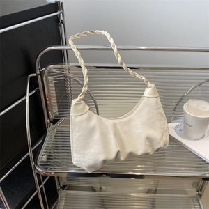 Chic pleated cream hobo bag with woven strap shown on a modern display stand