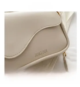 Detail view of cream leather shoulder bag featuring wavy flap and embossed JING PIN logo