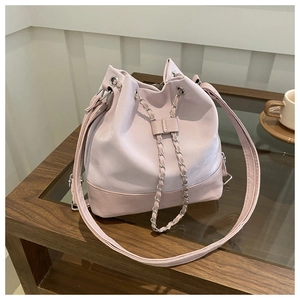 Detail of light purple bucket bag with metal chain drawstring on a wooden table