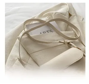 Detail view of adjustable shoulder strap and smooth cream leather on a crossbody bag