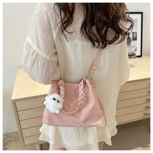 Dettaglio borsa hobo rosa con manici intrecciati e ciondolo in peluche sul modello