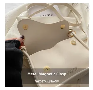Detail shot of the cream crossbody bag with a magnetic snap closure and embossed logo
