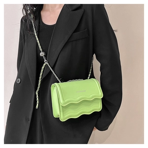 Détail du sac bandoulière vert citron avec rabat ondulé et bandoulière chaîne argent