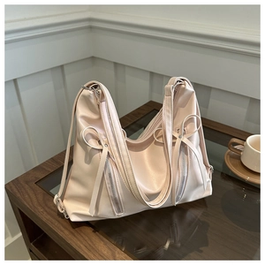 Détail du sac en cuir PU beige clair avec nœuds et fermetures éclair argentées