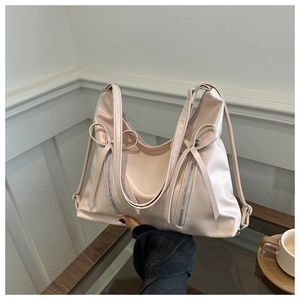 Détail du sac hobo rose clair avec nœuds décoratifs et fermetures éclair argentées