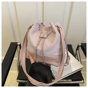 Pink drawstring bucket bag detail with chain accent and adjustable shoulder strap