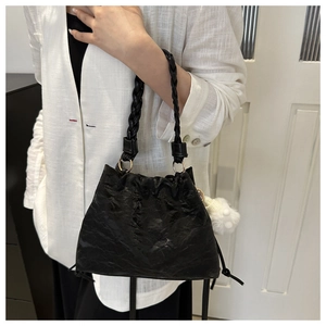 Dettaglio borsa shopper nera a pieghe con manico intrecciato, coulisse e pompon bianco