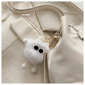 Close-up of white plush cartoon charm with knitted hat on leather chain bucket bag