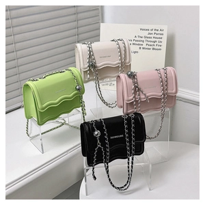 Détail de quatre sacs bandoulière en cuir avec bords ondulés et lanières en chaîne dorée