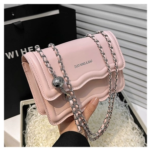 Détail d'un sac bandoulière rose avec chaîne argentée et breloque métallique