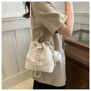 White drawstring bucket bag with silver chain and plush toy charm on model