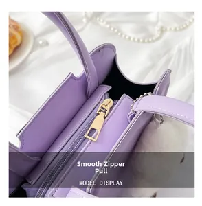 Detail of smooth gold zipper on lavender leather bag with soft white plush pendant