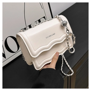Détail d'un petit sac bandoulière blanc cassé avec bords ondulés et chaîne argentée