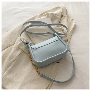 Dettaglio della borsa a tracolla azzurra minimalista con catena d'oro e texture in pelle