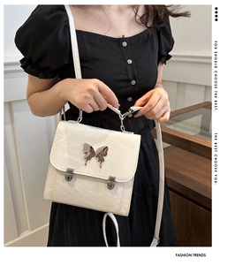 Detail of cream marbled crossbody bag featuring a silver metal butterfly buckle on flap