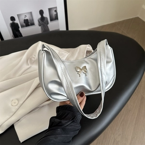 Silver metallic crescent moon bag with butterfly charm on a chic black bench