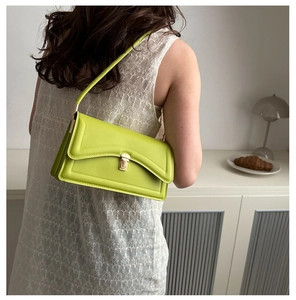 Detailed view of neon green crossbody bag with gold buckle on a model in a bright setting