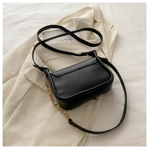 Dettaglio della borsa a tracolla in pelle nera con catena dorata su sfondo moda elegante