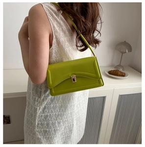 Detail of a bright green leather underarm bag with silver buckle on a stylish model