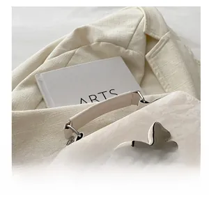Detailed view of cream textured leather bag featuring a large silver butterfly metal buckle