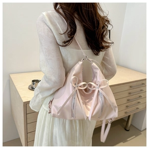 Détail du dos d'un sac à dos rose pâle avec nœuds et fermetures éclair sur un mannequin