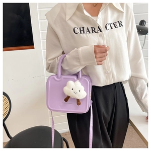 Detail of purple crossbody bag with plush cloud charm shown on model in white shirt