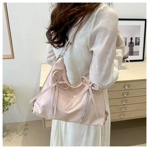 Sac à dos rose pâle avec nœuds porté par un mannequin dans un intérieur épuré