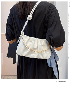 Detail of white pleated cloud bag featuring pearl chain and woven rope knot strap