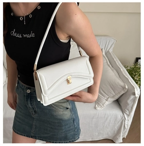 Close-up of white minimalist shoulder bag with vintage gold buckle on model