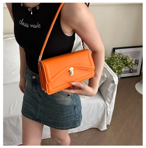 Close-up of bright orange fine leather shoulder bag with golden metallic clasp