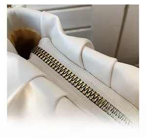 Close-up of white pebble leather bag showing gold zipper detail and smooth stitching
