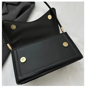 Detail of dual magnetic snap closures and leather texture on a black shoulder bag