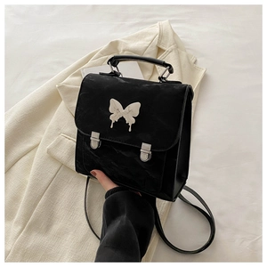 Detail of black faux leather backpack featuring marble butterfly charm and silver buckles