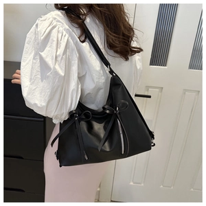 Détails d'un sac cabas en cuir noir avec zips argentés et décorations de nœuds