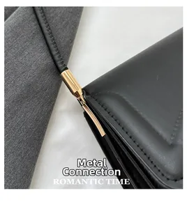Detail of gold metal hardware and fine stitching on a black leather crossbody bag