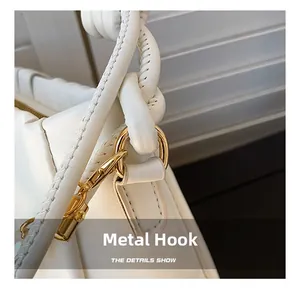 Detail of white lychee leather bag with gold hardware hook and woven knot strap