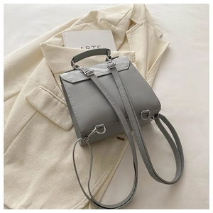 Detail of grey leather backpack featuring marble texture flap and silver hardware
