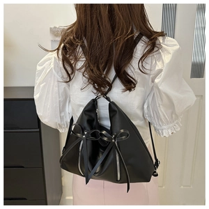 Gros plan d'un sac à dos en cuir noir avec détails de nœuds et fermetures éclair argent