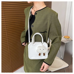 White faux leather crossbody bag detail featuring a cute plush cloud pendant accessory