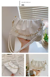 Close-up of off-white pleated cloud bag featuring decorative pearl and gold flower chain